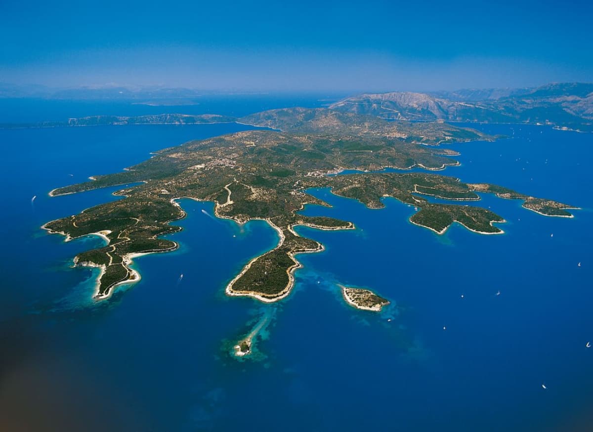 Ενα Dεραia Φωτογραφία ενός πράσινου νησιού με δαντελωτές ακτές και καταγάλανα νερά κάτω από καθαρό ουρανό.
