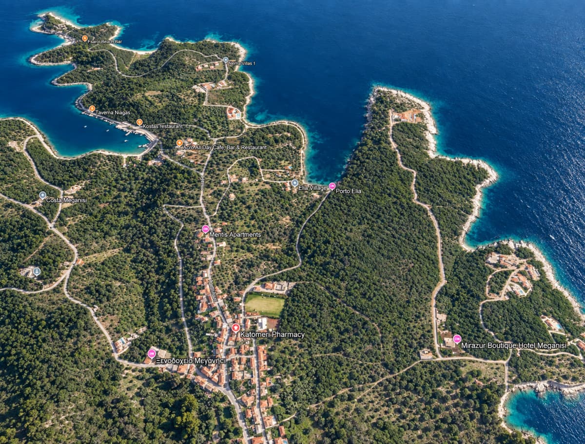 Ενα ψηφιακό αεροφωτογραφικό πλάνο μιας πράσινης παράκτιας περιοχής με δρόμους, κτίρια και μπλε νερά.