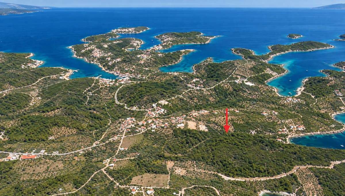 Αεροφωτογραφία που δείχνει μια πράσινη ακτογραμμή με σπίτια, δρόμους και νησιά στη θάλασσα.