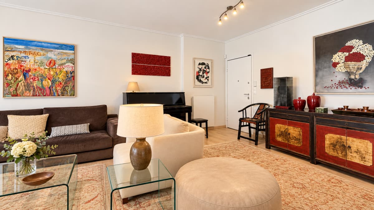 Living room with a brown sofa, cream armchair, piano, and Asian-inspired cabinetry.