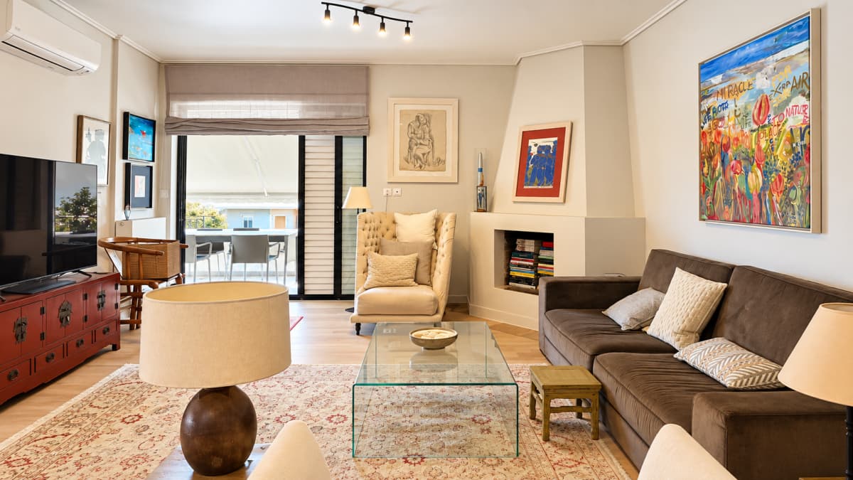 A living room with a brown sofa, glass coffee table, armchair, and fireplace.
