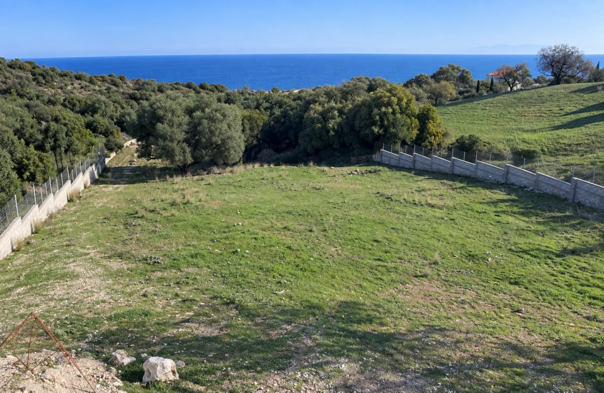 Ανηφορικό οικόπεδο με γκαζόν και περίφραξη προσφέρει θέα στη θάλασσα.