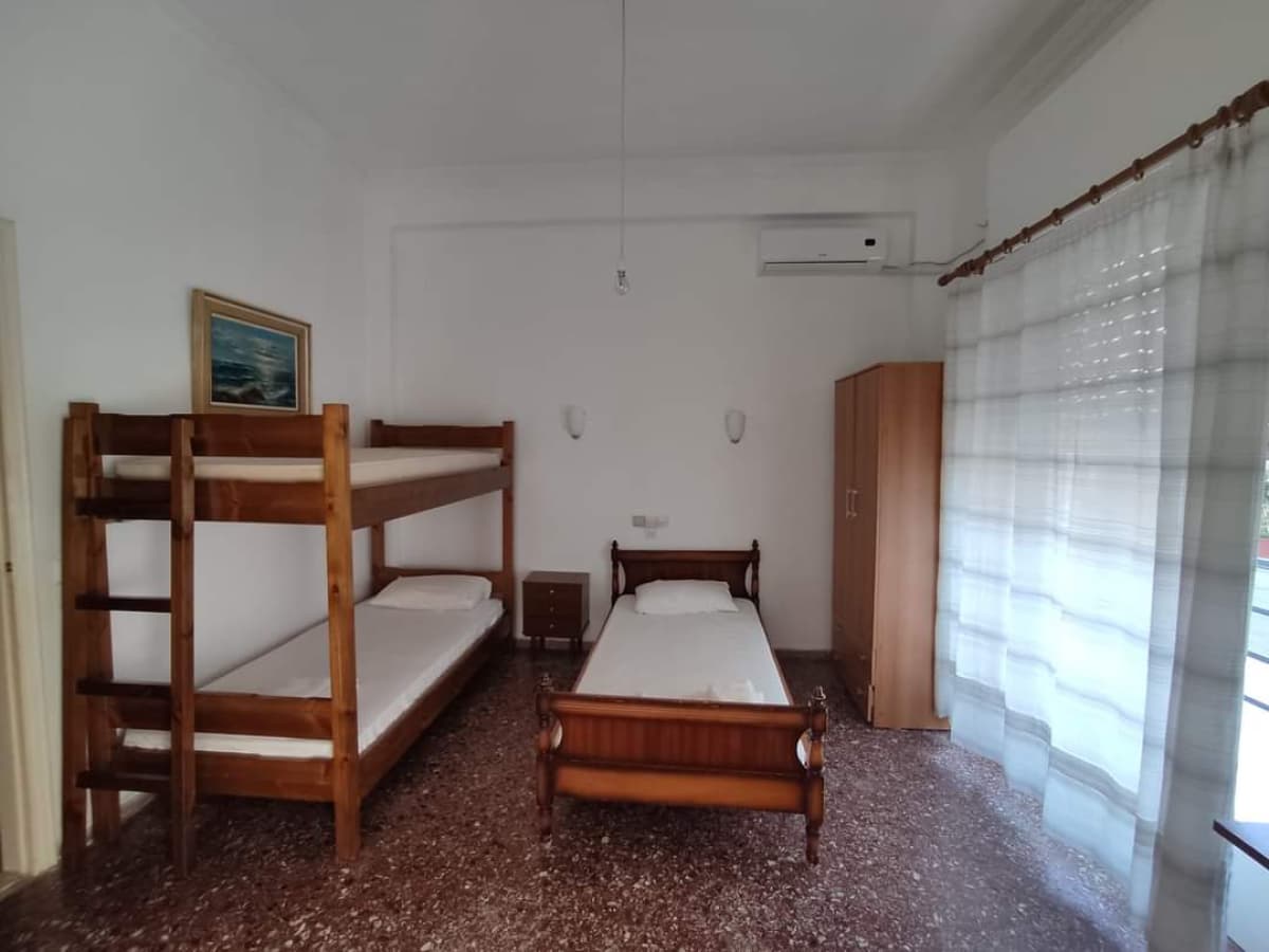 Υπνοδωμάτιο με κουκέτα, μονό κρεβάτι, ντουλάπα και παράθυρο με κουρτίνες.