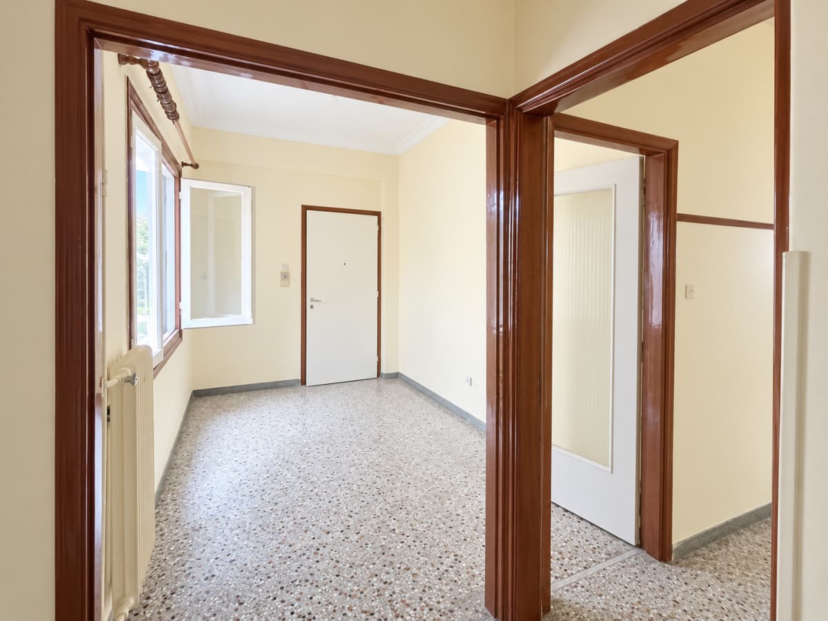 Hallway with wood doorframes, terrazzo flooring, and white doors.