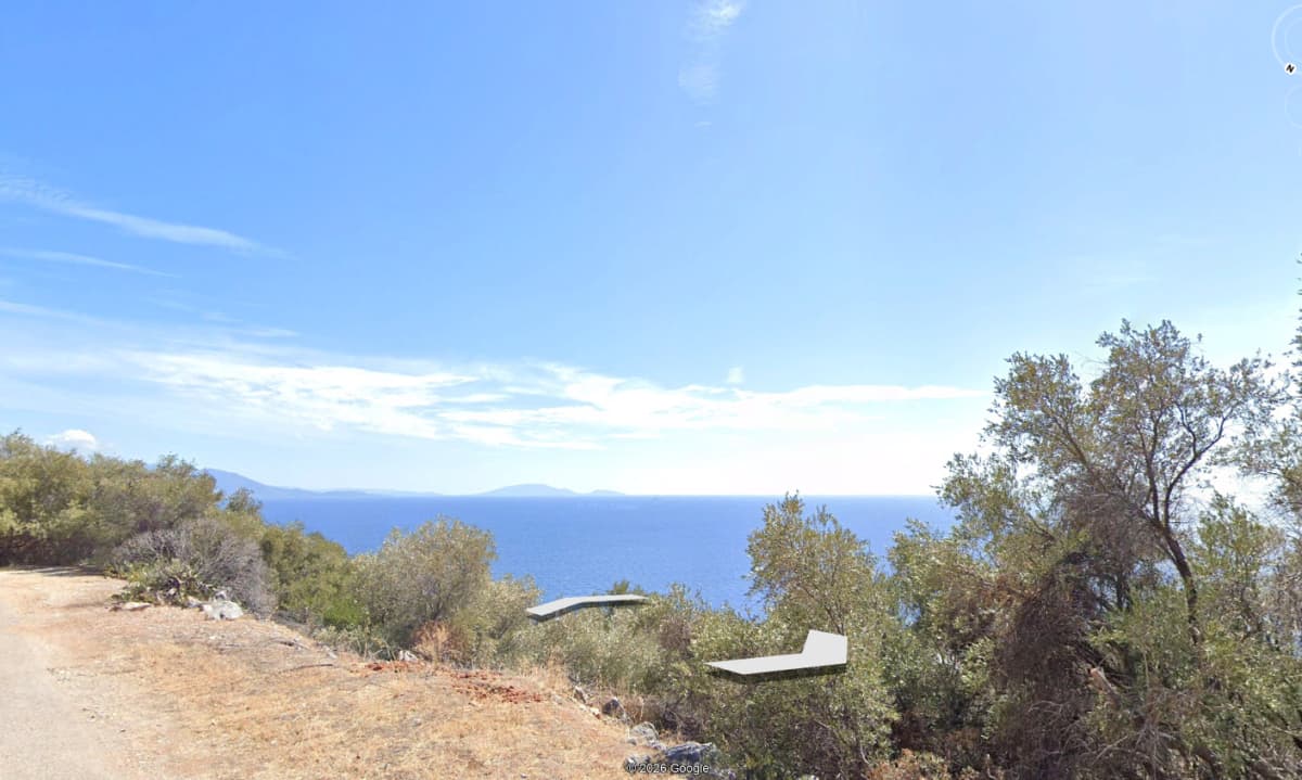 Εξωτερική θέα από χωματόδρομο προς τη θάλασσα με ελαιόδεντρα.