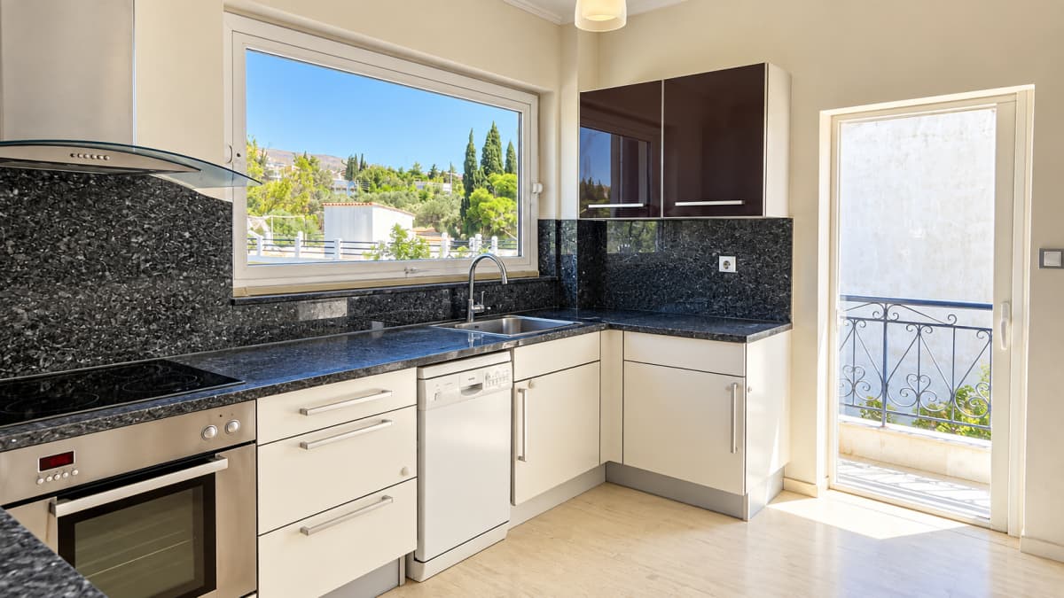 Kitchen with a dark stone worktop, white appliances and a door to a small balcony.