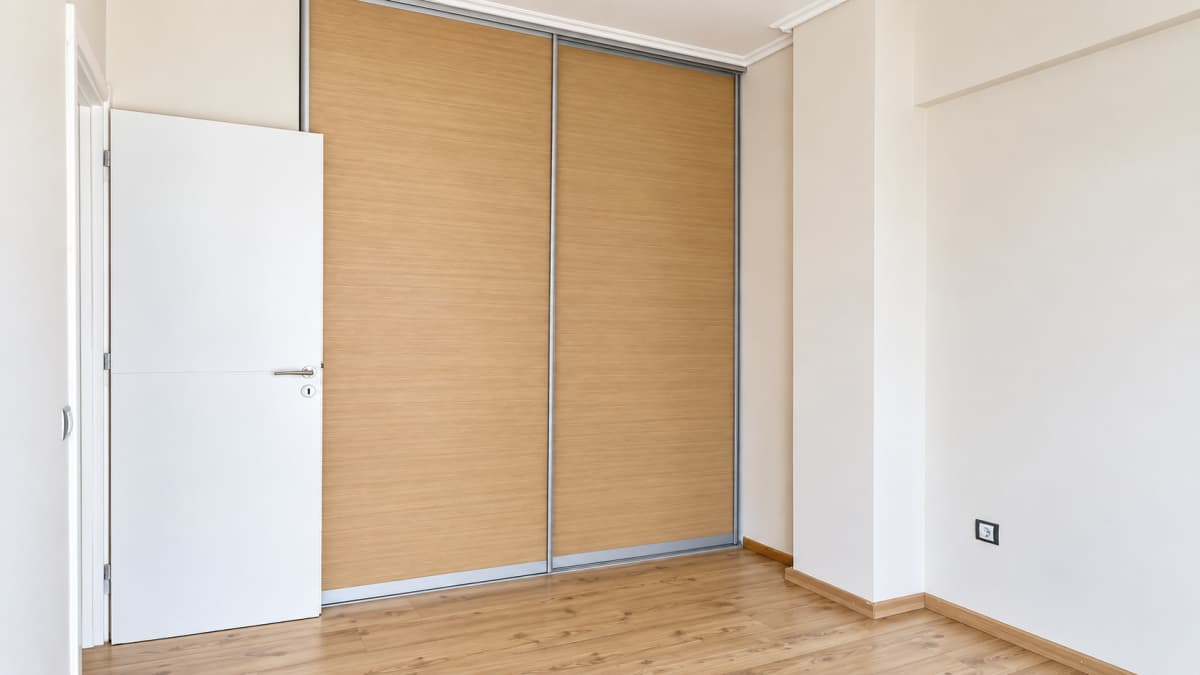 Bedroom corner with a built-in wardrobe with wood-effect sliding doors.