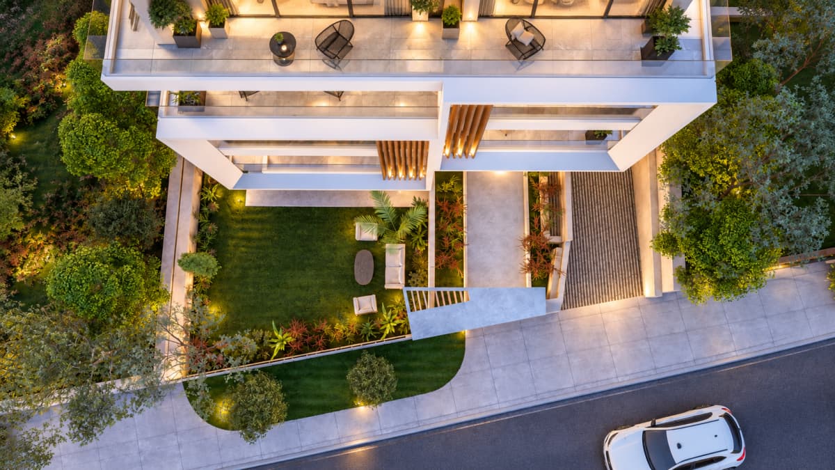 An aerial perspective shows a modern multi-story residential building with balconies, a landscaped front lawn with a seating area, and an adjacent driveway with a parked white car.