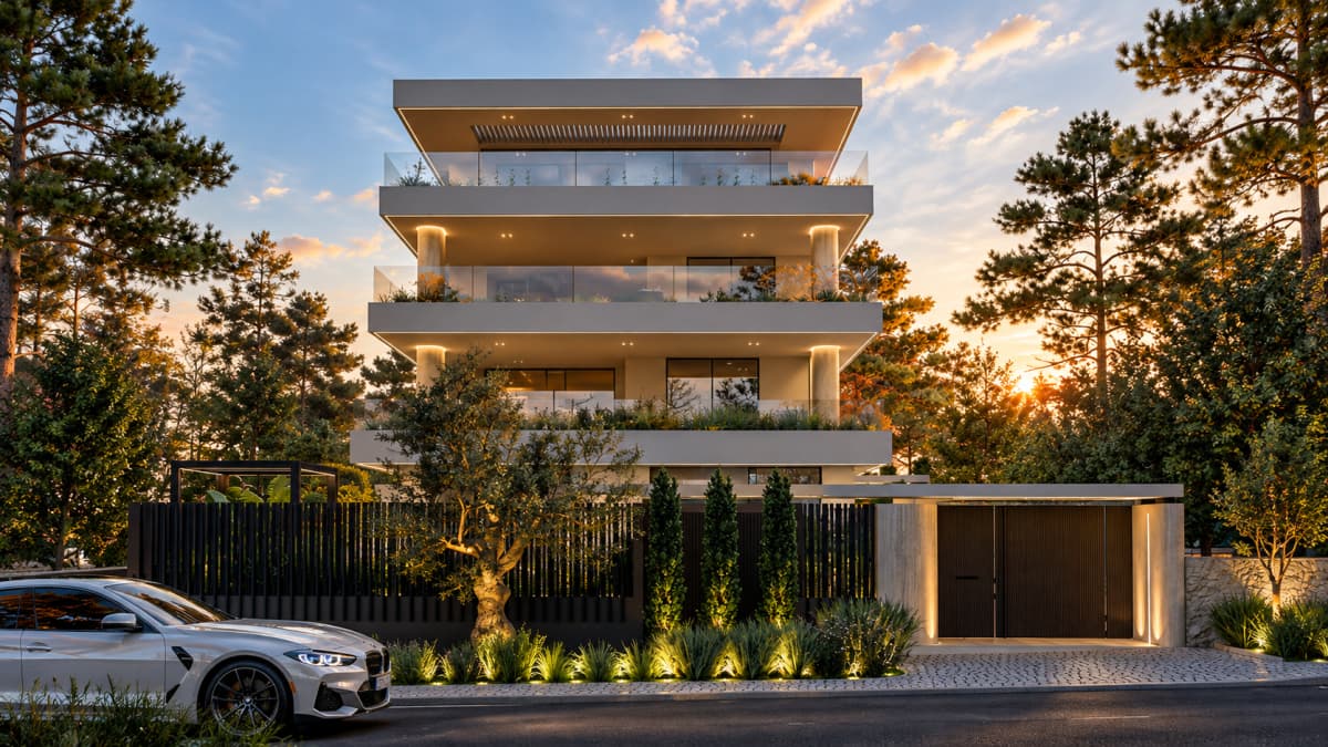 Front facade of a modern four-story apartment building with balconies, illuminated columns, fencing, and a parked car on the street.