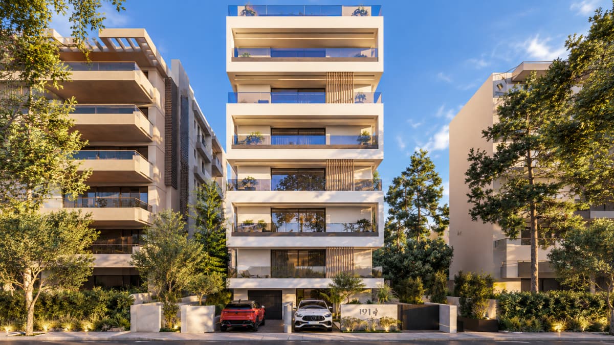 Εξωτερική θέα μιας σύγχρονης πολυκατοικίας με μπαλκόνια, πράσινο και δύο αυτοκίνητα στην είσοδο.