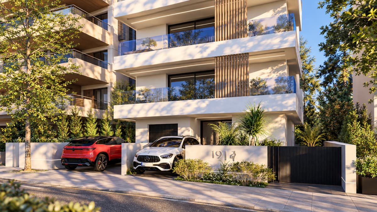 Exterior view of a modern multi-story apartment building with balconies, wood slat accents, and parked cars in the front driveway.